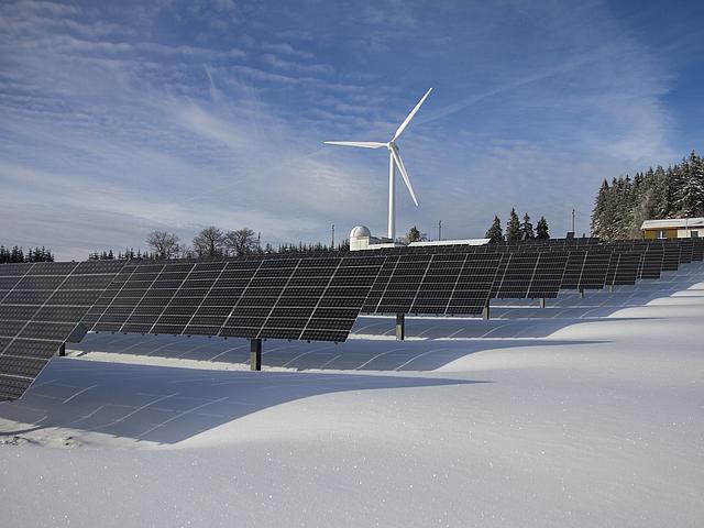Solarpark und Windkraftanlagen in Schnee-Landschaft