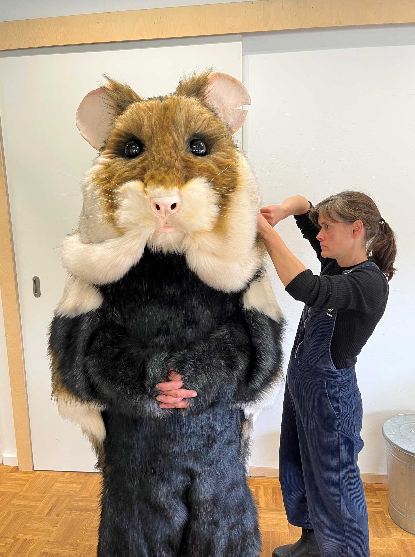 Mensch in Hamsterkostüm wird von einer Maskenbilderin fertig gemacht für den Dreh