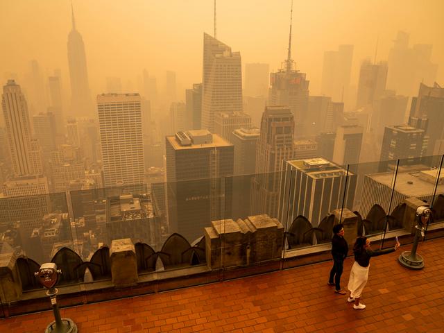 Blick von einem Hochhaus auf die Skyline von New York City eingehüllt in rötlichem Rauch