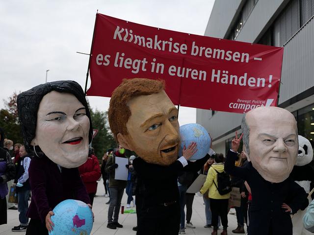 Karikaturen von Baerbock, Scholz und Lindner bei einer Demo.