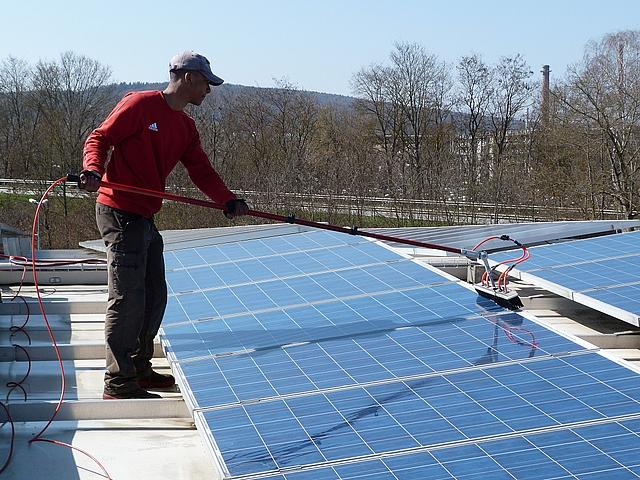 Arbeiter bei der Reinigung von Solarmodulen auf einem Dach