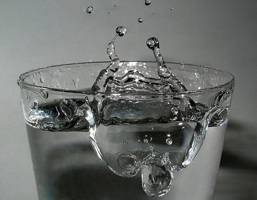 Wasserglas mit springenden Wassertropfen