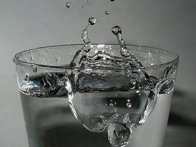 Wasserglas mit springenden Wassertropfen