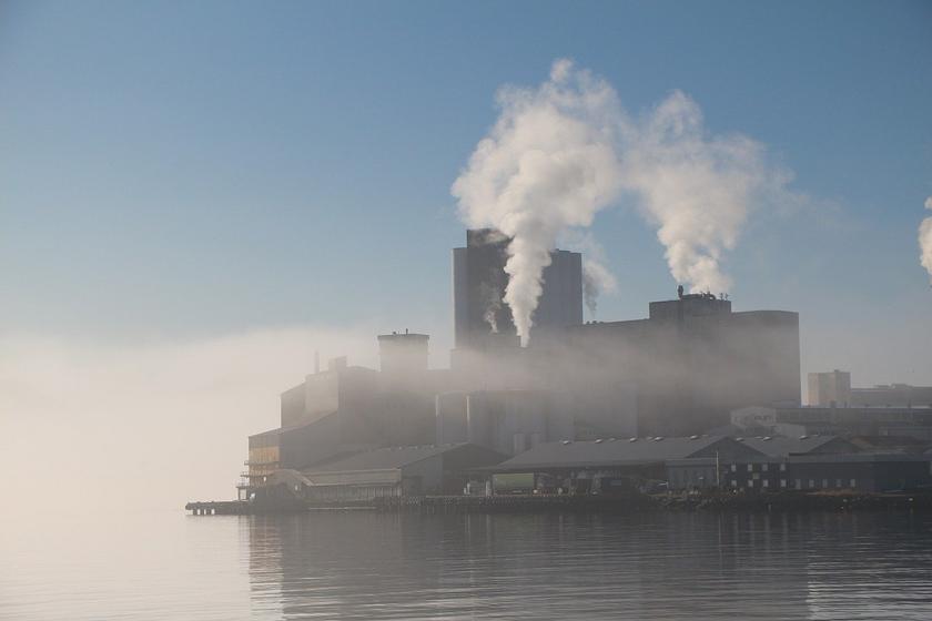 Industriebetrieb am Fjord in Norwegen im Nebel mit rauchenden Schloten