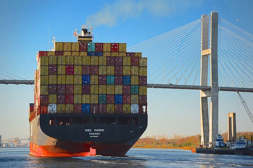 Foto eines Containerschiffs vor einer Brücke