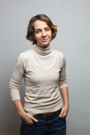 Eine Frau, mit halblangen braunen Haaren und in einem hellen Rollkragenpullover