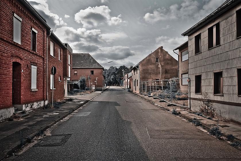 Bild einer verlassenen Straße in einem verlassenen Ort mit verlassenen Häusern am Wegesrand.