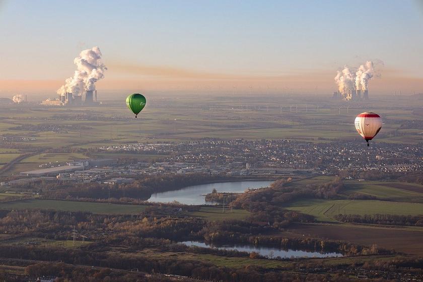 Heißluftballons über Landschaft mit Kohlekraftwerken