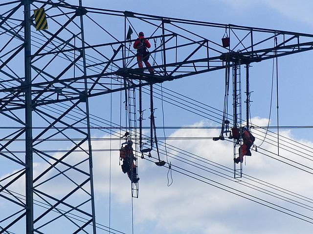 Arbeiter angeseilt an einem großen Strommast