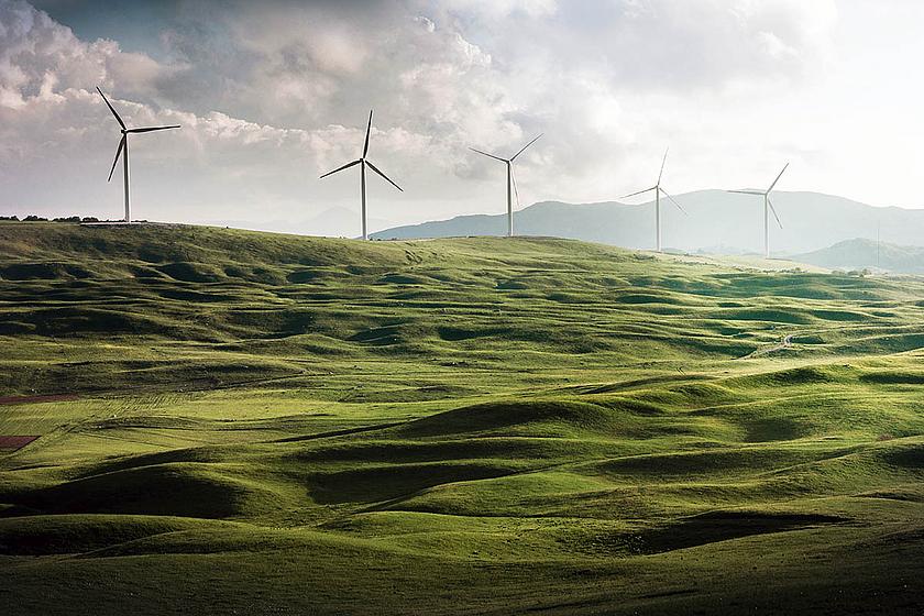 Windkraftanlagen zwischen grünen Hügeln