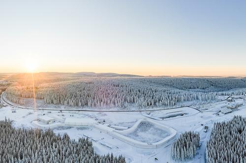 Luftaufnahme einer schneebedeckten Landschaft, mit Bäumen und Sportinfrastruktur 