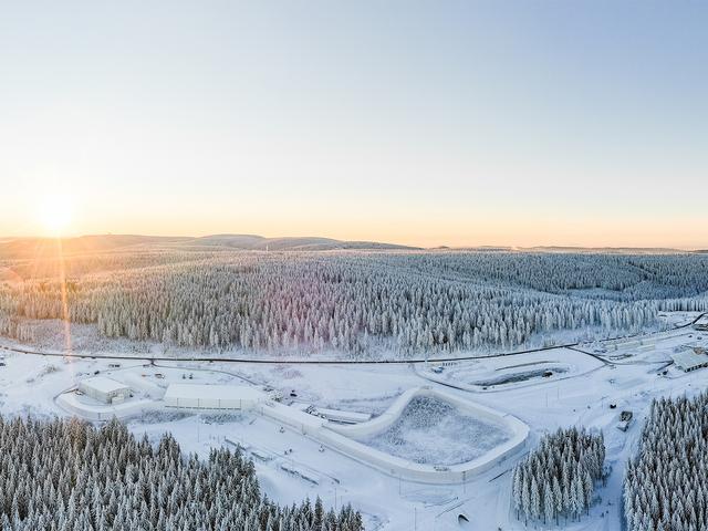 Luftaufnahme einer schneebedeckten Landschaft, mit Bäumen und Sportinfrastruktur 