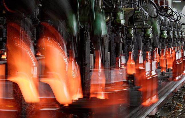 Industriemaschine, die Glasflaschen formt, das Glas ist flüssig orange