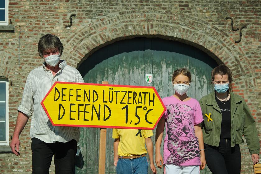 Ein Mann und zwei Frauen mit einem Schild auf dem steht: Defend 1,5 Grad - Defend Lützerath 