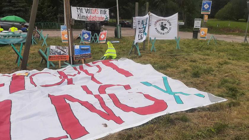 Auf einer Wiese stehen und liegen Plakate gegen LNG auf Rügen 