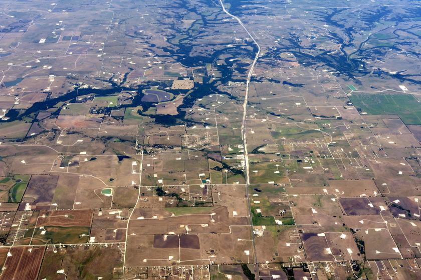 Luftaufnahme einer bräunlichen Landschaft, durchsetzt von weißen Flecken