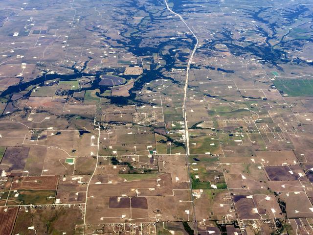 Luftaufnahme einer bräunlichen Landschaft, durchsetzt von weißen Flecken