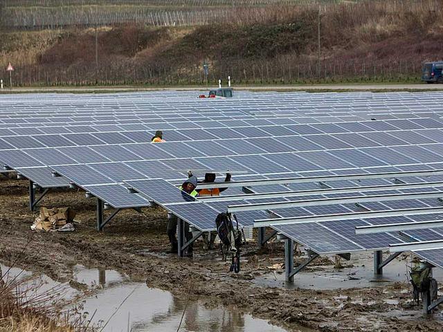 Arbeiter bei der Montage in einem Solarpark bei Regen