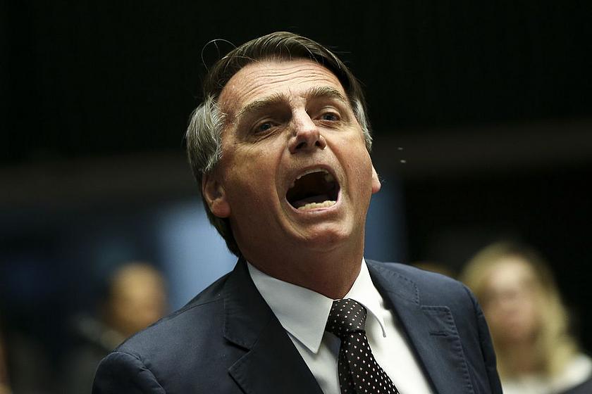 Nahaufnahme von Jair Bolsonaro im Anzug und weit aufgerissenem Mund.