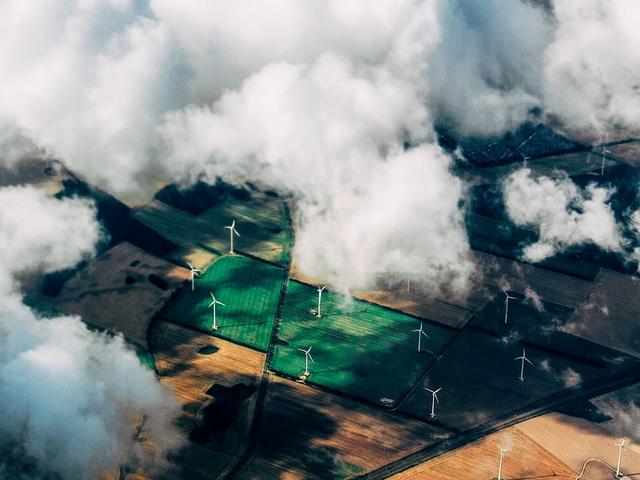 Windräder auf Feldern mit Wolkendecke aus der Vogelperspektive