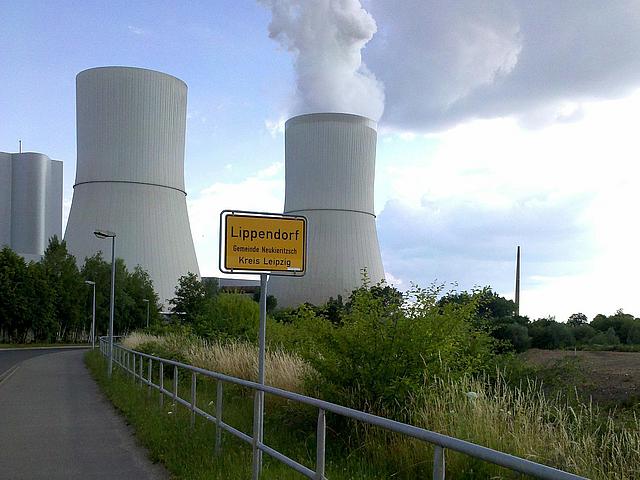 Ortsschild von Lippendorf im Kreis Leipzig. Im Hintergrund die rauchenden Kühltürme des örtlichen Braunkohlekraftwerks.