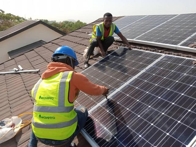 Zwei afrikanische Installateure installieren Solaranlage auf einem Dach