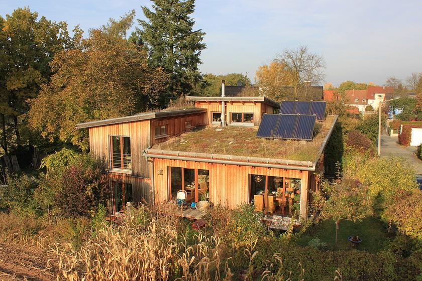 Ein Haus aus Holz mit Dachbegrünung und Solarpanels