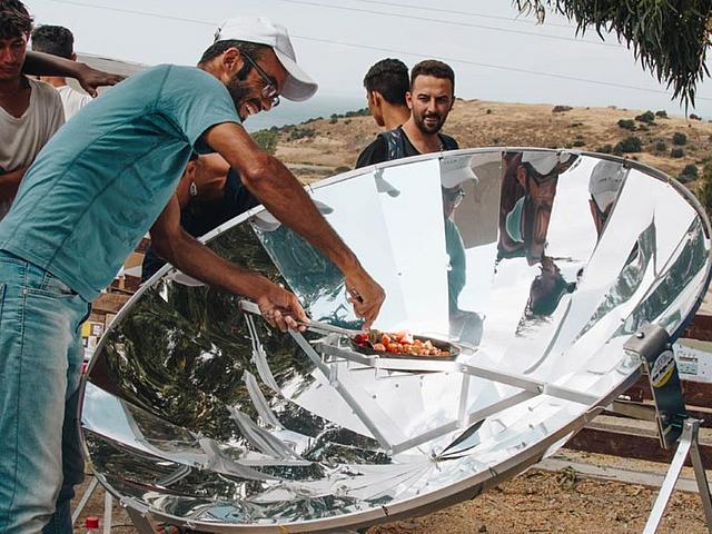 Menschen vor einem Solarkocher