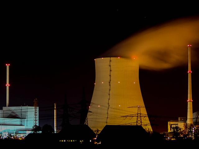 Atomkraftwerk mit rauchendem Wasserdampf bei Nacht