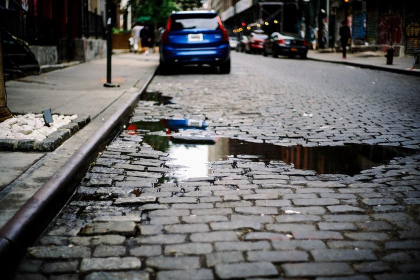 Gepflasterte Straße mit Wasserpfütze und Auto
