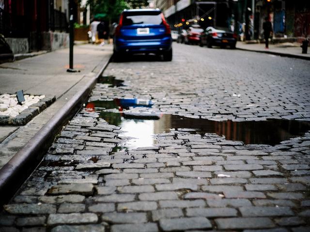 Gepflasterte Straße mit Wasserpfütze und Auto