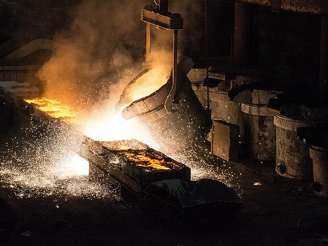 Bild einer Ferro-Legierung in der sogenannten Metallurgie. Aus einem riesigen Trog wird flüssiges Metall in Kästen geschüttet.