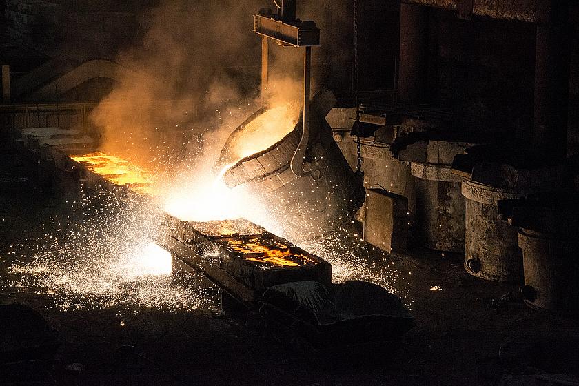 Bild einer Ferro-Legierung in der sogenannten Metallurgie. Aus einem riesigen Trog wird flüssiges Metall in Kästen geschüttet.