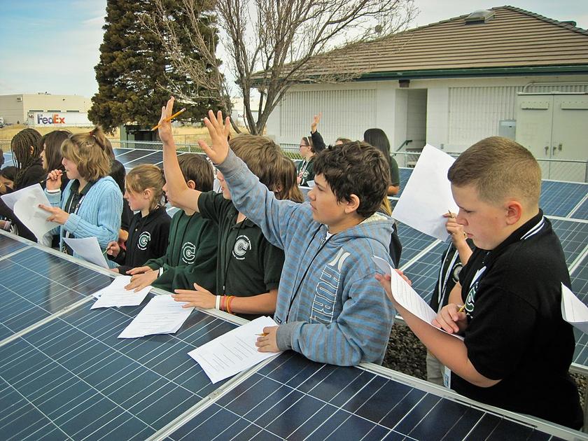 Schulunterricht zwischen Modulreihen einer Solaranlage