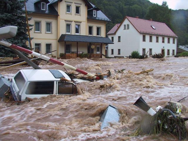 Überflutung nach Starkregen: Auto, Bahnschranke, andere Gegenstände in reißenden Wassermassen