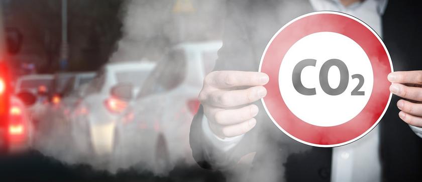 Stop-CO2-Schild, im Hintergrund Abgase vom Verkehr