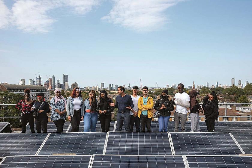 Junge Menschen auf einem Dach mit Solaranlage