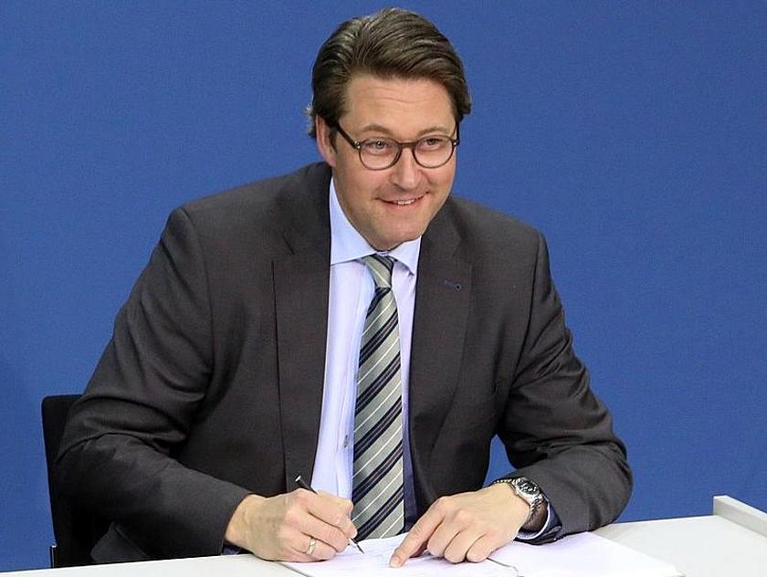 Andreas Scheuer sitzend. Unterzeichnet ein Papier