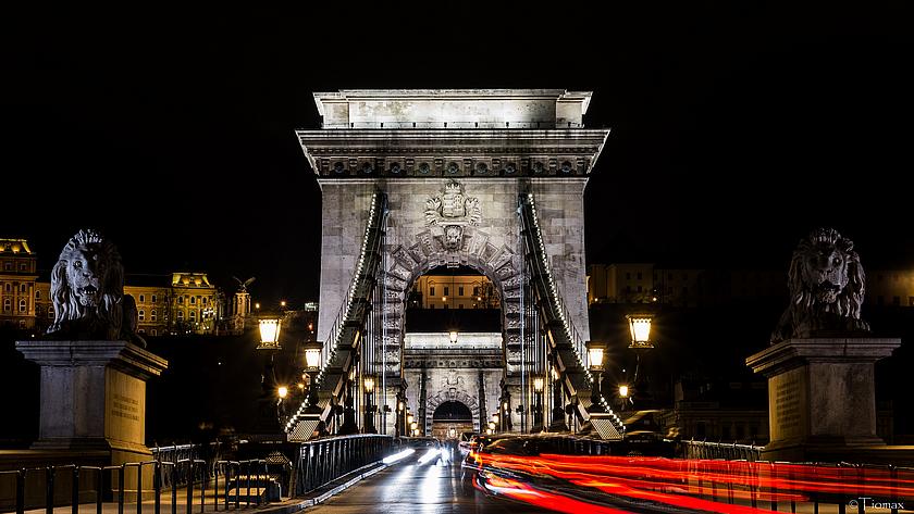 Nachtaufnahme einer Brücke in Budapest, über die Autos fahren.