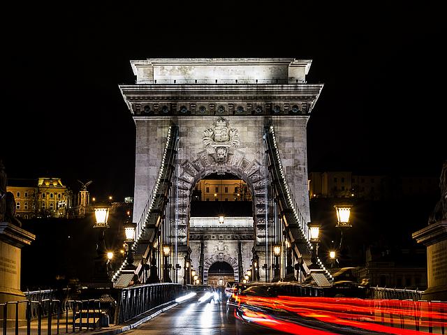 Nachtaufnahme einer Brücke in Budapest, über die Autos fahren.