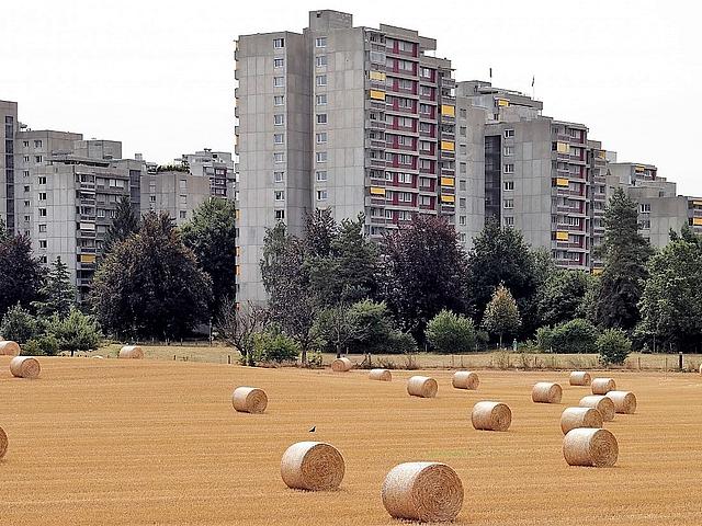 Hochhäuser vor einem Feld mit Strohballen