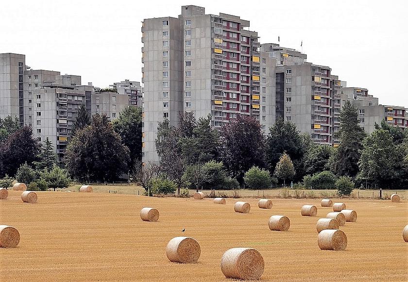 Hochhäuser vor einem Feld mit Strohballen