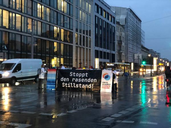 Protest von Scientist Rebellion in Berlin, Menschen mit Transparent auf regennasser Straße