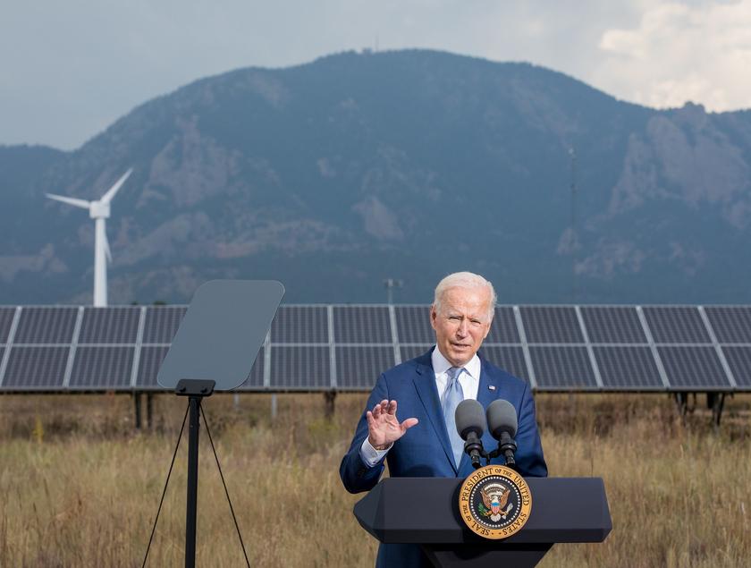 Ein Mann im Anzug vor einem Pult bei einer Rede. Im Hintergrund sind Solarpanels zu sehen.