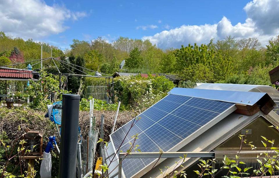 zwei Solarmodule auf einem Gewächshaus im Kleingarten