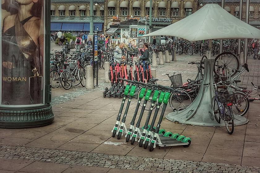 E-Scooter auf einem Bahnhofsplatz inmitten tausender abgestellter Fahrräder.