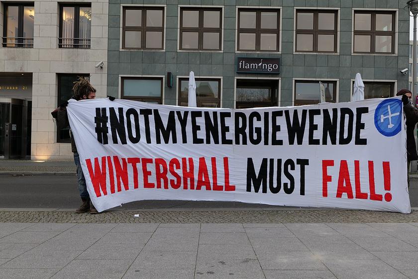 Mensch mit Plakat und der Aufschrift "Not my Energiewende. Wintershall must fall"