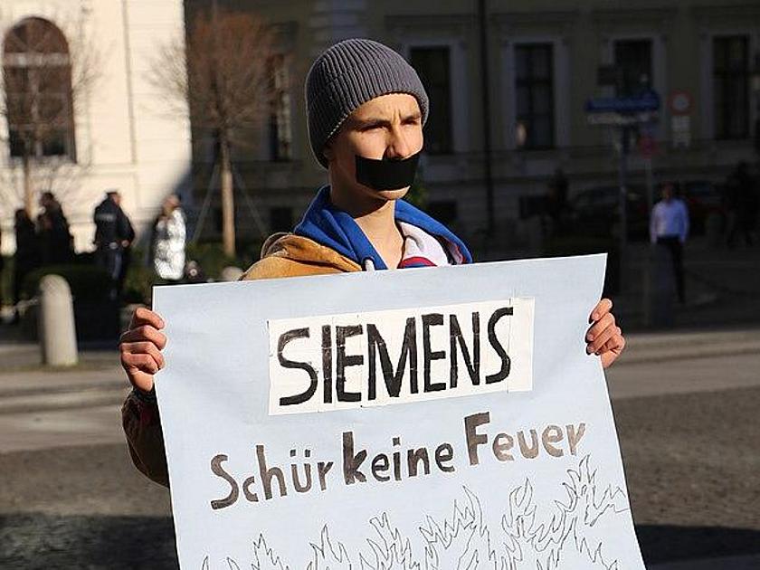 Aktivist von Fridays for Future mit einem Schild, auf dem steht: "Siemens schür keine Feuer"