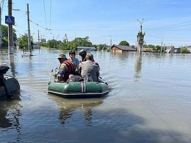 Menschen sitzen in einem Schlauchboot in einem überschwemmten Gebiet