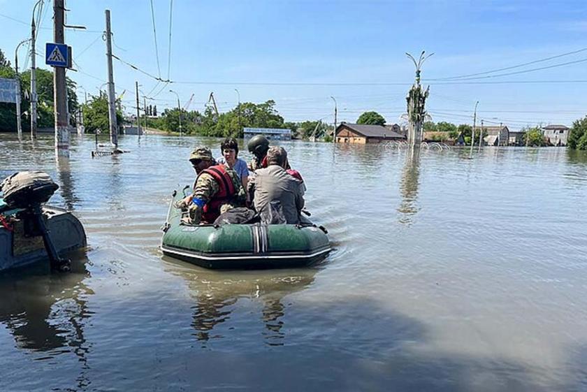 Menschen sitzen in einem Schlauchboot in einem überschwemmten Gebiet